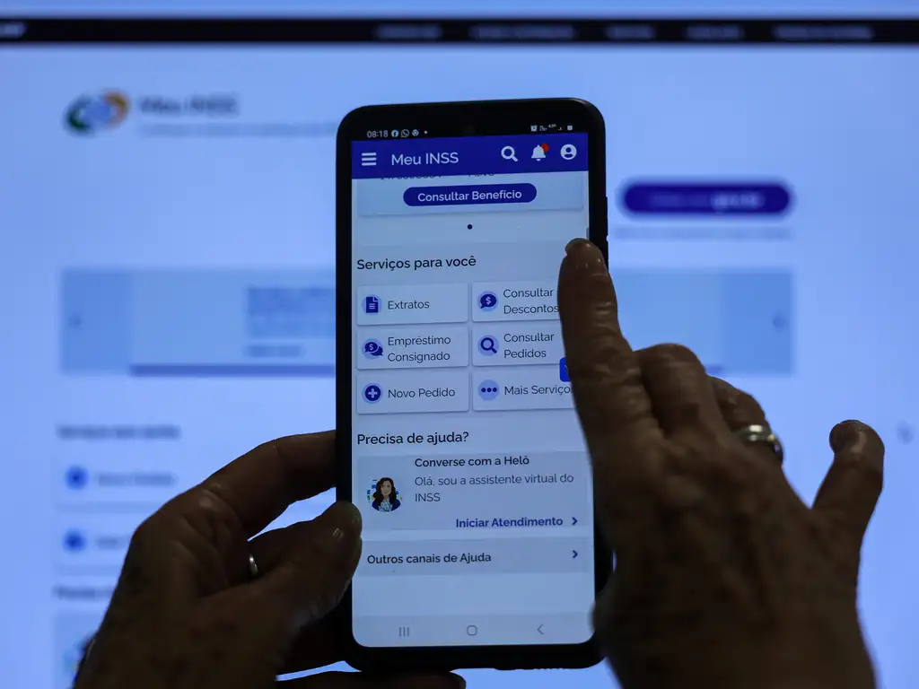 Aplicativo Meu INSS: Plataforma Segura para Consultar Benefícios e a Prova de Vida Mãos segurando um celular com o aplicativo oficial "Meu INSS" aberto na tela principal de serviços e consulta de benefícios.
