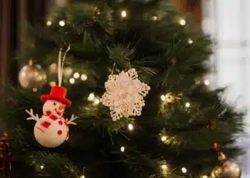 Imagem de uma árvore de Natal tradicional com enfeites e luzes de Natal.
