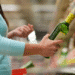 Mulher segurando garrafa de azeite verde enquanto escolhe produto em prateleira de supermercado