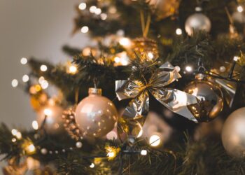 Árvore de Natal decorada com luzes cintilantes e bolas douradas, representando o início das festividades e a data ideal para a montagem em 2025.