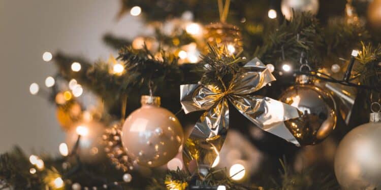 Árvore de Natal decorada com luzes cintilantes e bolas douradas, representando o início das festividades e a data ideal para a montagem em 2025.