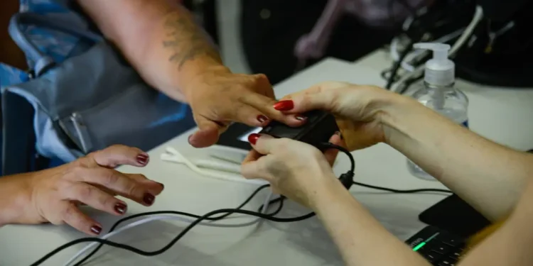 Pessoa com pele morena tendo dedo medido por oxímetro digital segurado por mãos claras