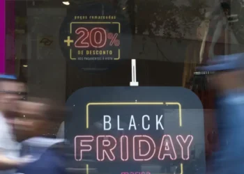 Letreiro luminoso anunciando Black Friday com desconto de 20% em loja com movimento de pessoas