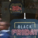 Letreiro em vitrine anunciando Black Friday com desconto adicional de 20% em peças remarcadas para pagamento à vista