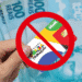 Ilustração sobre bloqueio de benefícios do Bolsa Família, com cartão riscado e notas de 100 reais ao fundo.