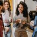 Grupo diversificado de colegas sorrindo e conversando durante uma pausa para café, ilustrando networking informal e conexões profissionais inesperadas.