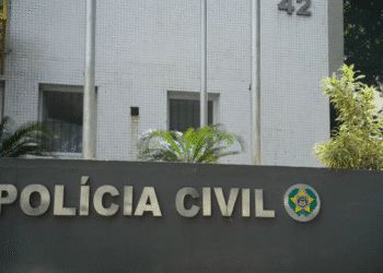 Fachada da Polícia Civil com letras metálicas e símbolo oficial em uma parede cinza