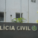 Fachada da Polícia Civil com letras metálicas e símbolo oficial em uma parede cinza