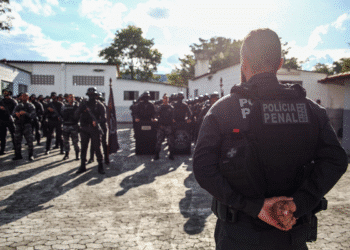 Policial Penal de costas, observando tropa em formação, simbolizando o concurso público para 1.100 vagas da Polícia Penal de SP.