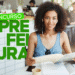 Imagem de uma jovem mulher com cabelo cacheado, usando fones de ouvido brancos e óculos pendurados na blusa, sorrindo enquanto lê um livro em uma cafeteria moderna, com o texto "CONCURSO PREFEITURA" em verde sobreposto.