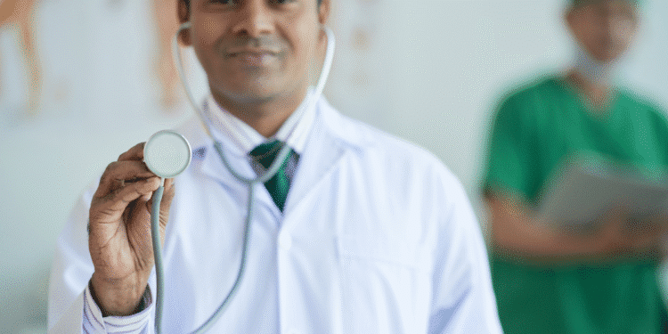 Médico sorridente com jaleco branco e gravata segurando estetoscópio em foco
