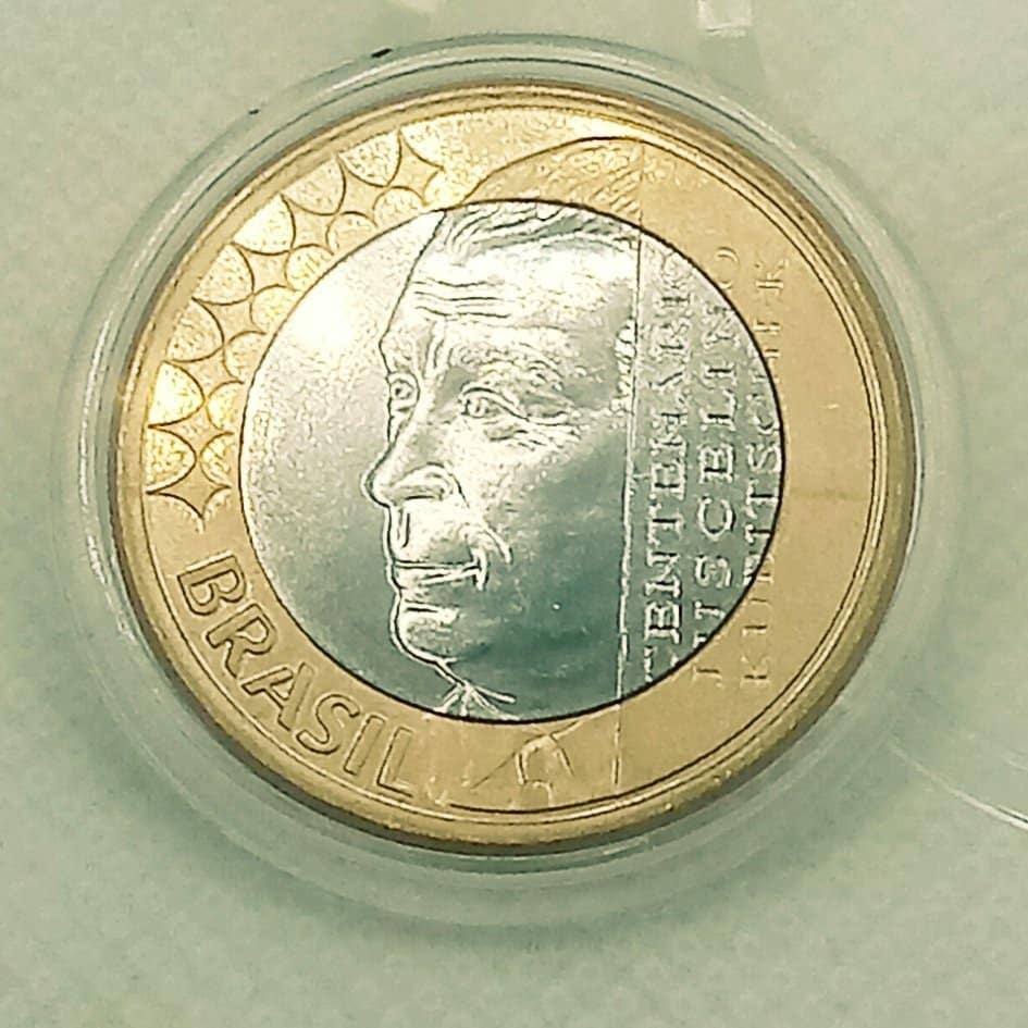 Moeda Rara de 1 Real JK: Quanto Vale o Centenário de Juscelino Kubitschek Moeda comemorativa brasileira de 1 Real, em cápsula protetora, com a efígie de Juscelino Kubitschek (JK) e o texto 'Centenário JK'.