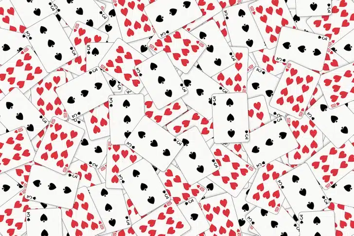 Desafio visual com uma montagem de várias cartas de baralho de paus, copas e espadas espalhadas aleatoriamente.