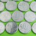 Close-up de diversas moedas brasileiras de 50 centavos, algumas com datas como 1994, 1995 e 2008, procuradas por colecionadores de moedas raras.