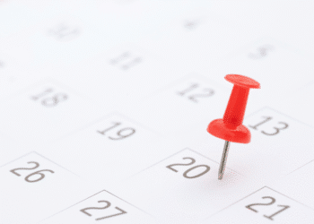 Alfinete vermelho destacado no dia 20 de um calendário branco com números pretos