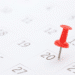 Alfinete vermelho destacado no dia 20 de um calendário branco com números pretos