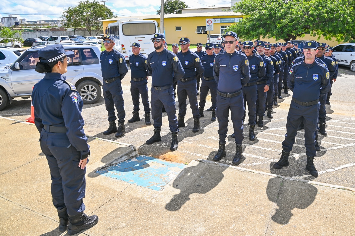 Agentes uniformizados da guarda municipal alinhados em treinamento ao ar livre.