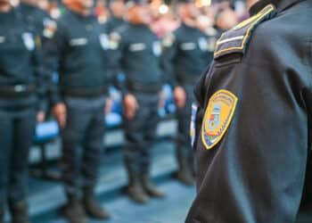 Guarda Municipal em formação, com uniforme preto e brasão da corporação em destaque no ombro.