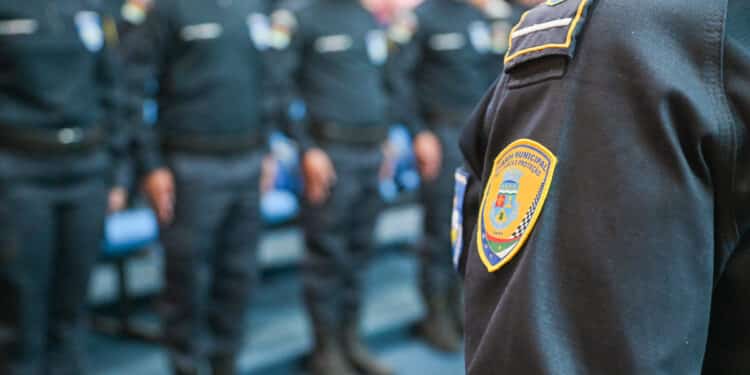 Guarda Municipal em formação, com uniforme preto e brasão da corporação em destaque no ombro.