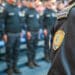 Guarda Municipal em formação, com uniforme preto e brasão da corporação em destaque no ombro.