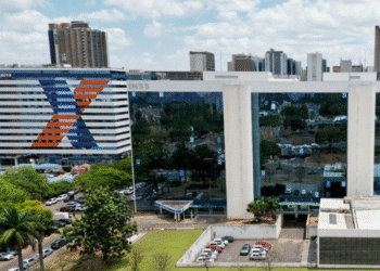 Prédio do INSS e da Caixa com arquitetura modernista e fachada espelhada refletindo árvores e carros ao redor