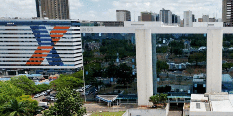 Prédio do INSS e da Caixa com arquitetura modernista e fachada espelhada refletindo árvores e carros ao redor