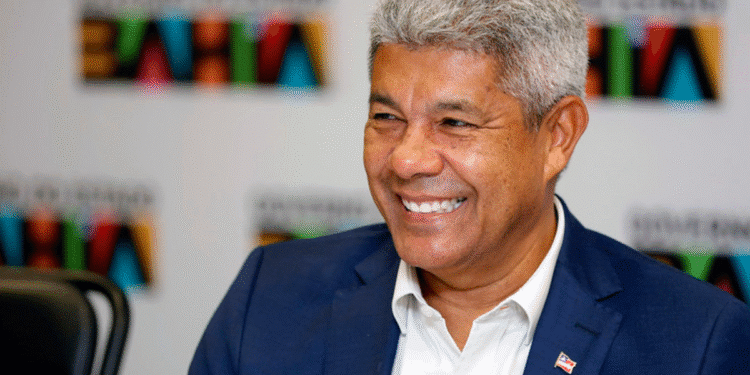 Governador Jerônimo Rodrigues sorrindo durante evento oficial com fundo escrito Governo da Bahia