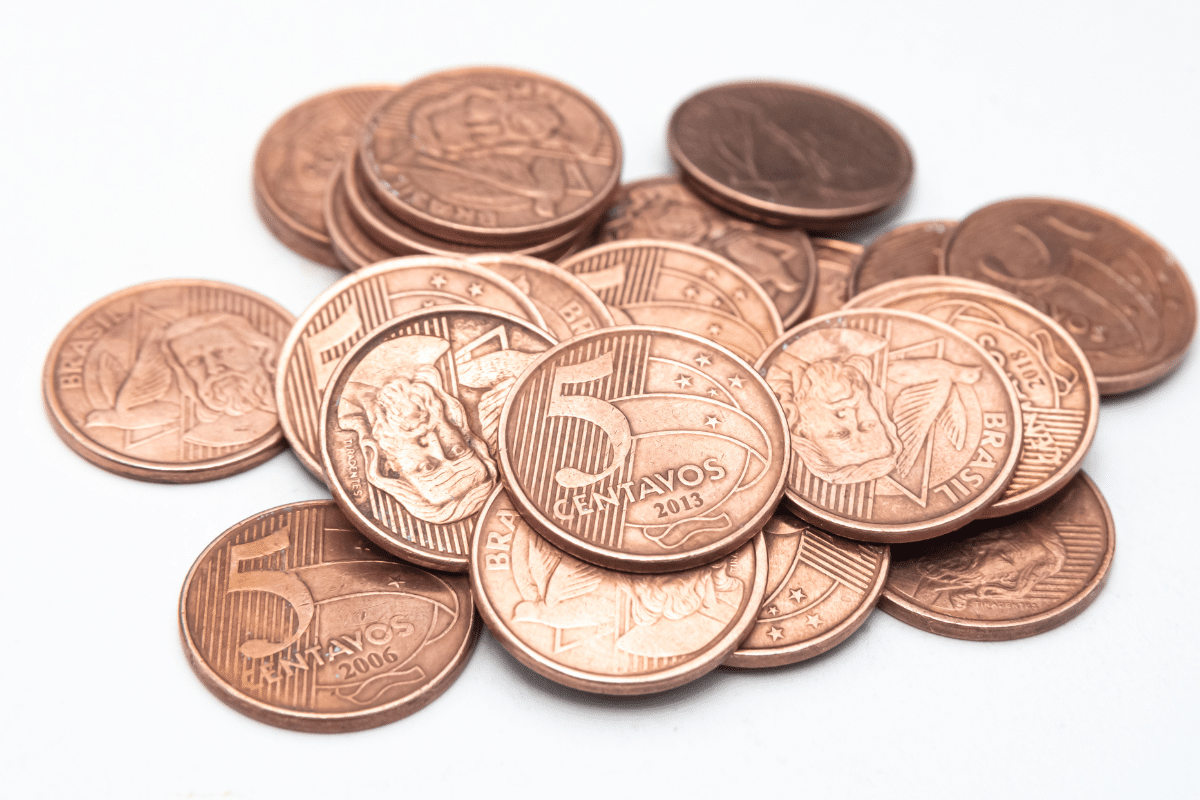 Pilha de moedas brasileiras de 5 centavos de cobre com detalhes das estrelas e do rosto de Pedro Álvares Cabral