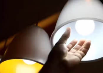 Lâmpada incandescente acesa com fundo preto destacando detalhes internos