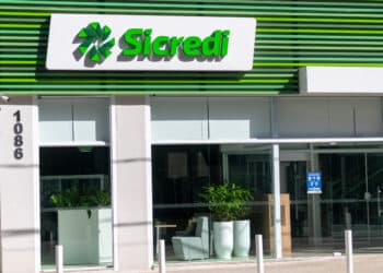 Fachada moderna da agência Sicredi com painéis verdes e logo iluminado em branco e verde