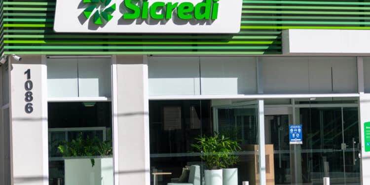 Fachada moderna da agência Sicredi com painéis verdes e logo iluminado em branco e verde