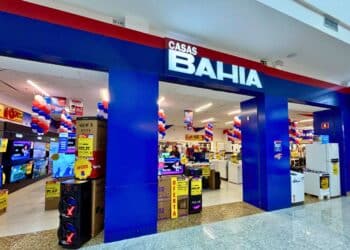 Entrada da loja Casas Bahia com decoração em azul, vermelho e branco, exibindo produtos eletrônicos em promoção