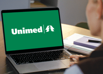 Computador com logo verde da Unimed na tela sendo usado por uma pessoa