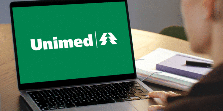 Computador com logo verde da Unimed na tela sendo usado por uma pessoa