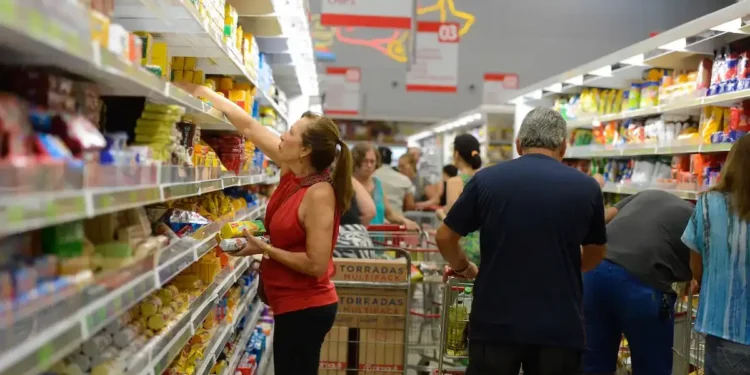 Supermercado cheio com consumidores comprando alimentos, ilustrando o impacto das novas regras do vale-refeição e vale-alimentação.