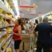 Supermercado cheio com consumidores comprando alimentos, ilustrando o impacto das novas regras do vale-refeição e vale-alimentação.