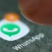 Foto da tela do celular mostrando o ícone do WhatsApp com uma notificação laranja e dedo próximo ao ícone