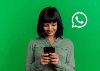 Mulher sorridente mexendo no celular com fundo verde e ícone do WhatsApp ao lado