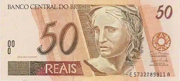 Cédulas Raras R$ 50 R$ 100 Valor Alto Flor Estampa Mão segurando notas de R$ 100 Reais, representando cédulas de alto valor. A imagem simboliza as notas raras de R$ 50 (Onça Pintada) e R$ 100 (Garoupa) que valem mais de R$ 5.800 em perfeito estado de conservação.