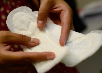 Pessoa segurando um absorvente aberto enquanto verifica o material do produto.