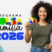 Mulher sorridente segurando o cartão do Bolsa Família ao lado do logotipo colorido do programa e o ano 2026. No canto inferior, aparecem notas de real.