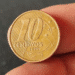 Close-up da face da moeda de 10 centavos, exibindo claramente o ano de 1999. A imagem destaca o valor nominal da moeda que, devido a um erro de cunhagem, pode valer até R$ 150.
