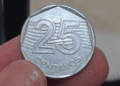 Close-up de uma moeda de 25 centavos sendo segurada, destacando a necessidade de análise minuciosa para encontrar o erro de confecção que pode multiplicar seu valor no mercado de colecionadores.