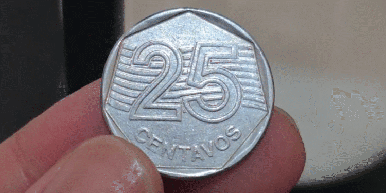 Close-up de uma moeda de 25 centavos sendo segurada, destacando a necessidade de análise minuciosa para encontrar o erro de confecção que pode multiplicar seu valor no mercado de colecionadores.