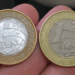 Close-up de diversas moedas de 1 real brilhantes agrupadas sobre uma superfície, destacando o desenho e o ano de fabricação.