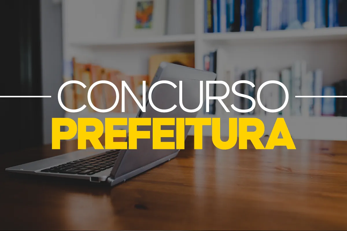 Notebook aberto sobre mesa de madeira com estante de livros ao fundo representando estudos para concurso.