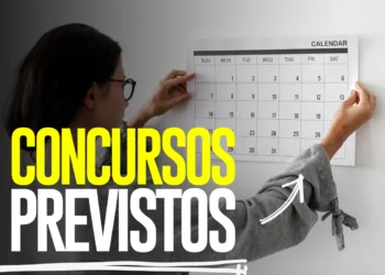 Mulher com óculos pendura calendário na parede com títulos em amarelo e branco sobre concursos previstos