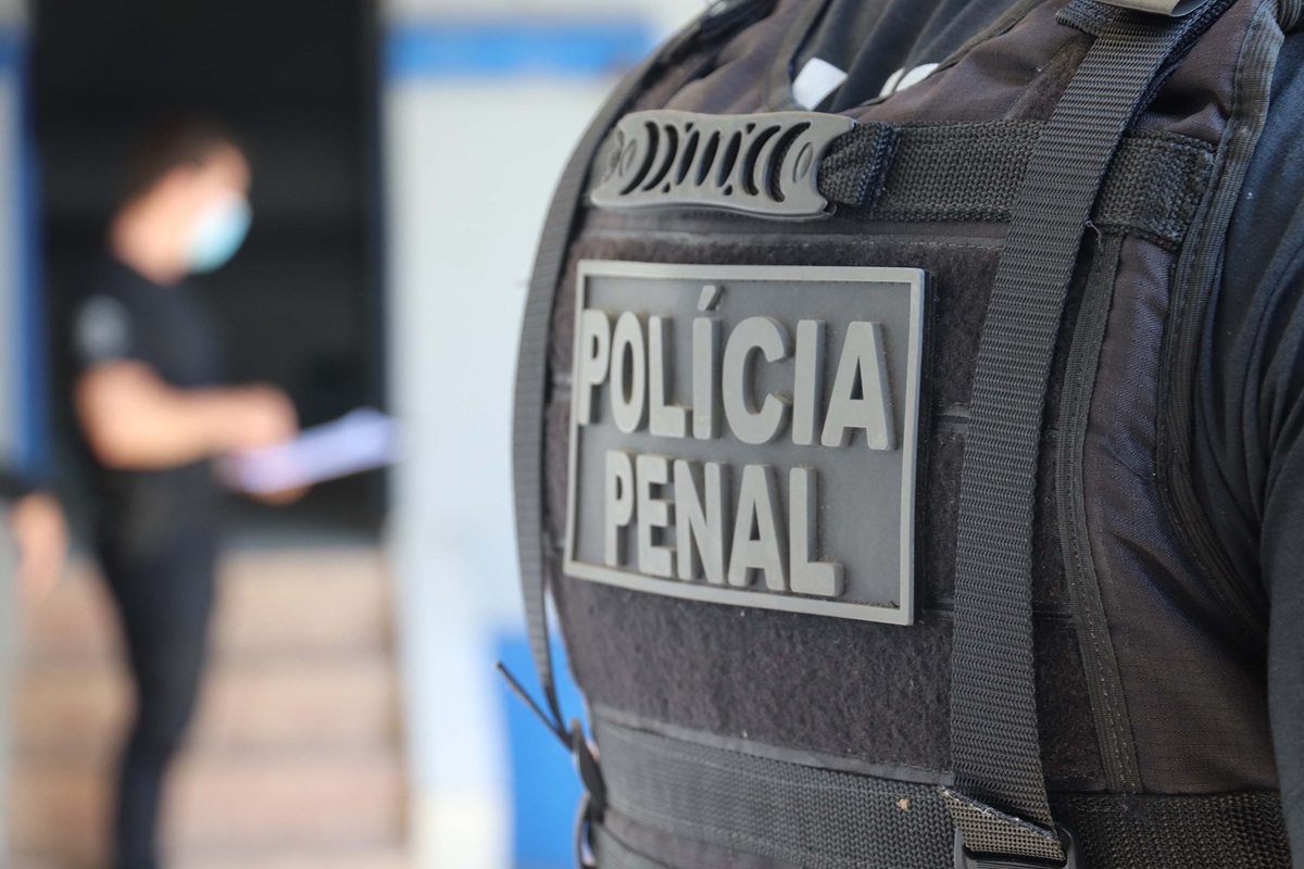 Agente da Polícia Penal em serviço com colete tático oficial.