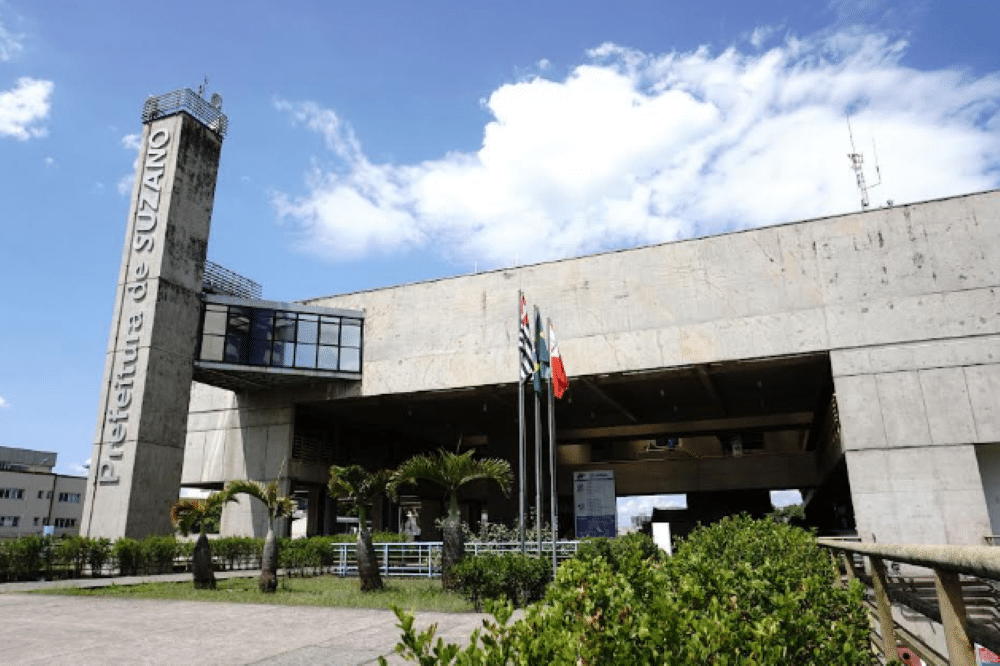 Concurso Prefeitura de Suzano - SP Fachada do prédio da Prefeitura de Suzano com bandeiras hasteadas ao centro.