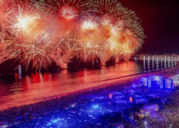 Queima de fogos no Réveillon com milhares de pessoas reunidas à beira-mar durante celebração de Ano Novo